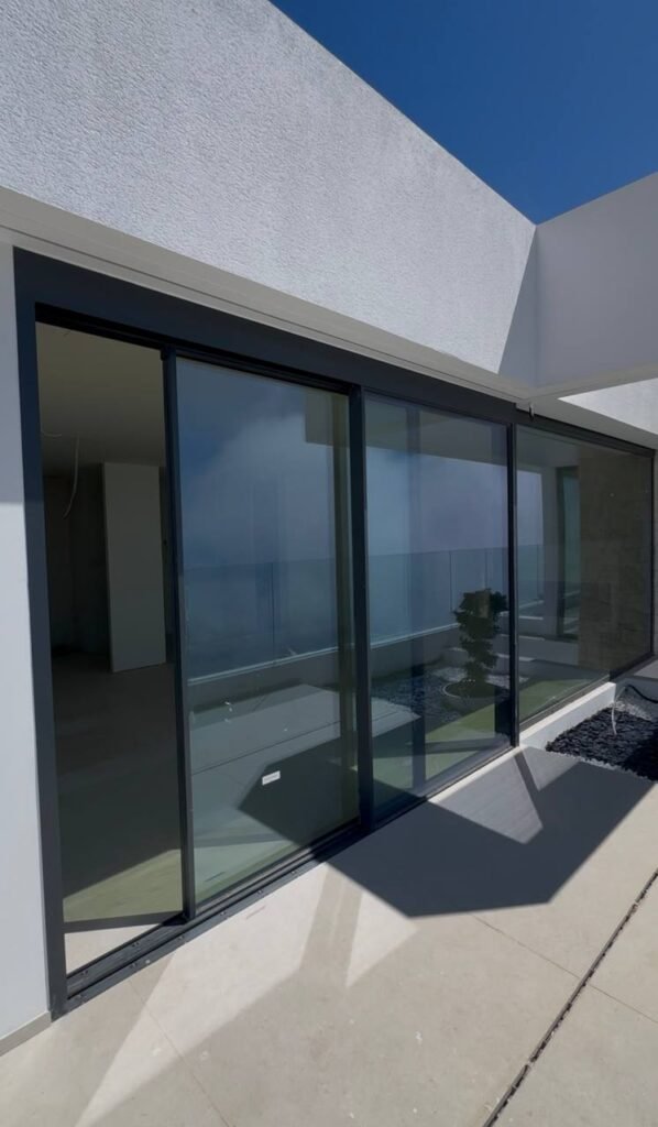 Fachada de villa de lujo con grandes ventanales y sistemas correderos de aluminio