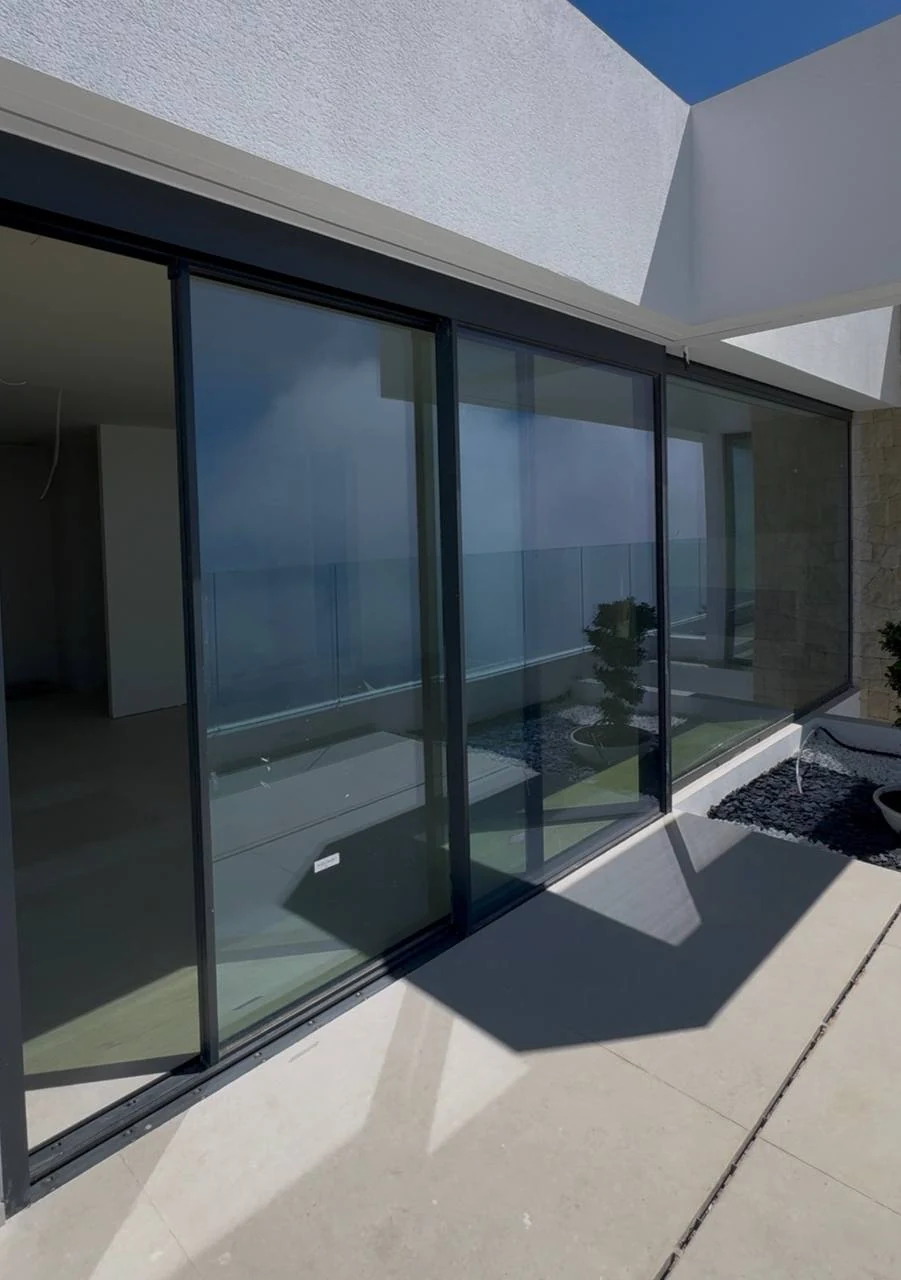 Großformatige Schiebetüren mit dunklen Profilen am Terrassenaustritt eines Hauses mit Meerblick