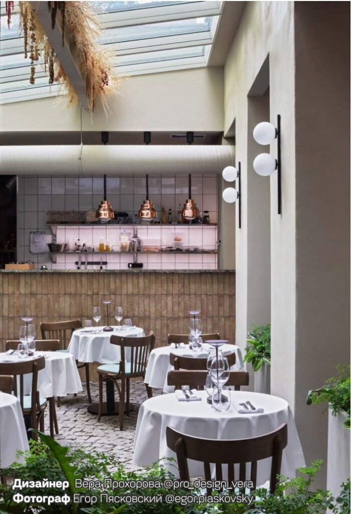 Comedor de restaurante con mesas de mantel blanco bajo un techo acristalado
